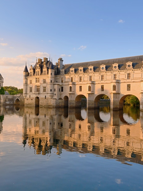Chenonceau Castle reflecting on the Cher River at sunset, France.