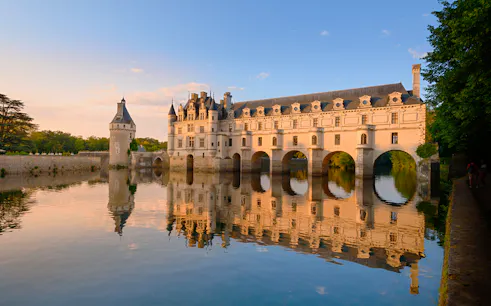 Chenonceau Castle reflecting on the Cher River at sunset, France.