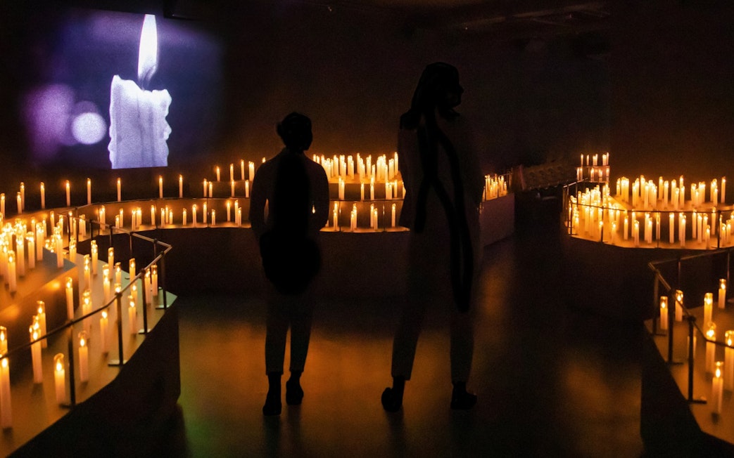 Guests explore candle-lit room at Mythos Mozart Immersive Experience in Vienna.