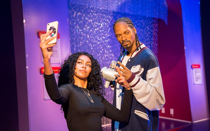 Person taking selfie with wax figure at Madame Tussauds Los Angeles.