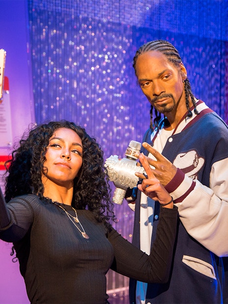 Person taking selfie with wax figure at Madame Tussauds Los Angeles.