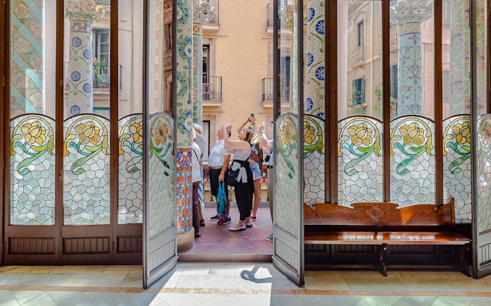 Tourists photographing stained glass and mosaic columns at Palau de la Musica Catalana.