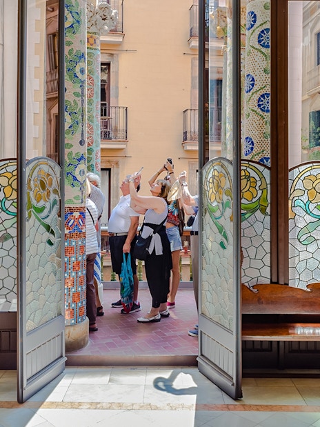 Tourists photographing stained glass and mosaic columns at Palau de la Musica Catalana.