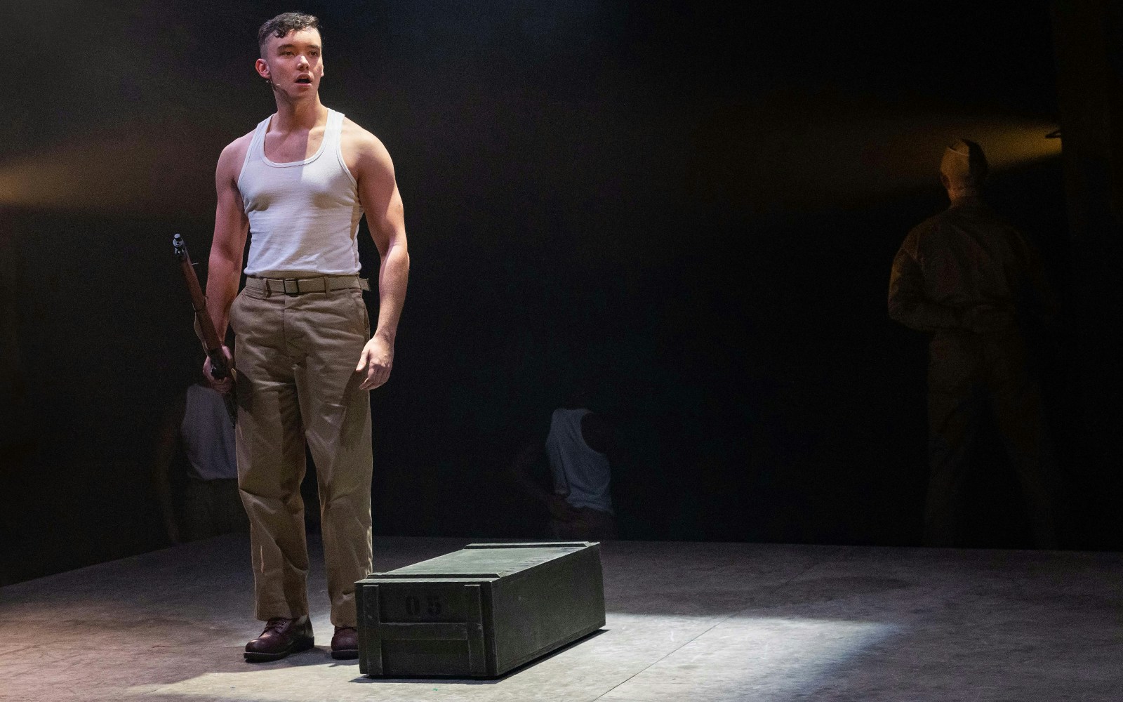 Soldier on stage holding a rifle in "From Here To Eternity – The Musical" performance.