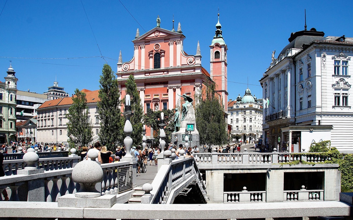 Dragon Bridge in Ljubljana with view of historic buildings and bustling square.