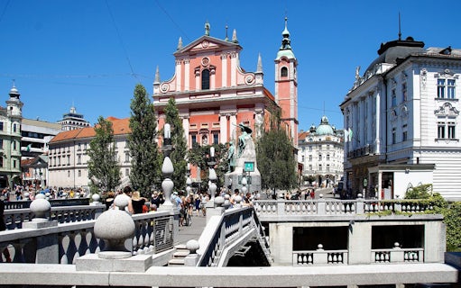 Dragon Bridge in Ljubljana with view of historic buildings and bustling square.