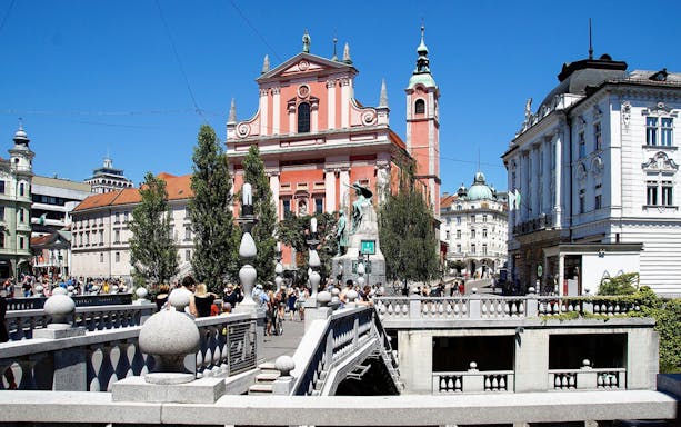 Dragon Bridge in Ljubljana with view of historic buildings and bustling square.