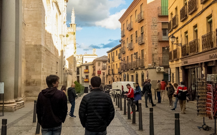 Tourists walking along a historic street with traditional architecture in Toledo, Spain.