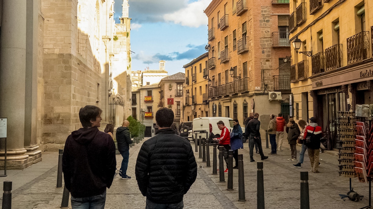 Tourists walking along a historic street with traditional architecture in Toledo, Spain.