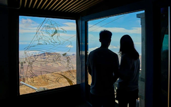 Guests viewing Mount Teide landscape through a window with artistic design.