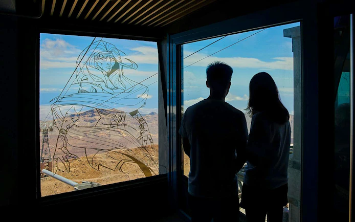 Guests viewing Mount Teide landscape through a window with artistic design.