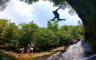 Canyoning adventure in Iriomote, Okinawa with a person jumping near a waterfall.