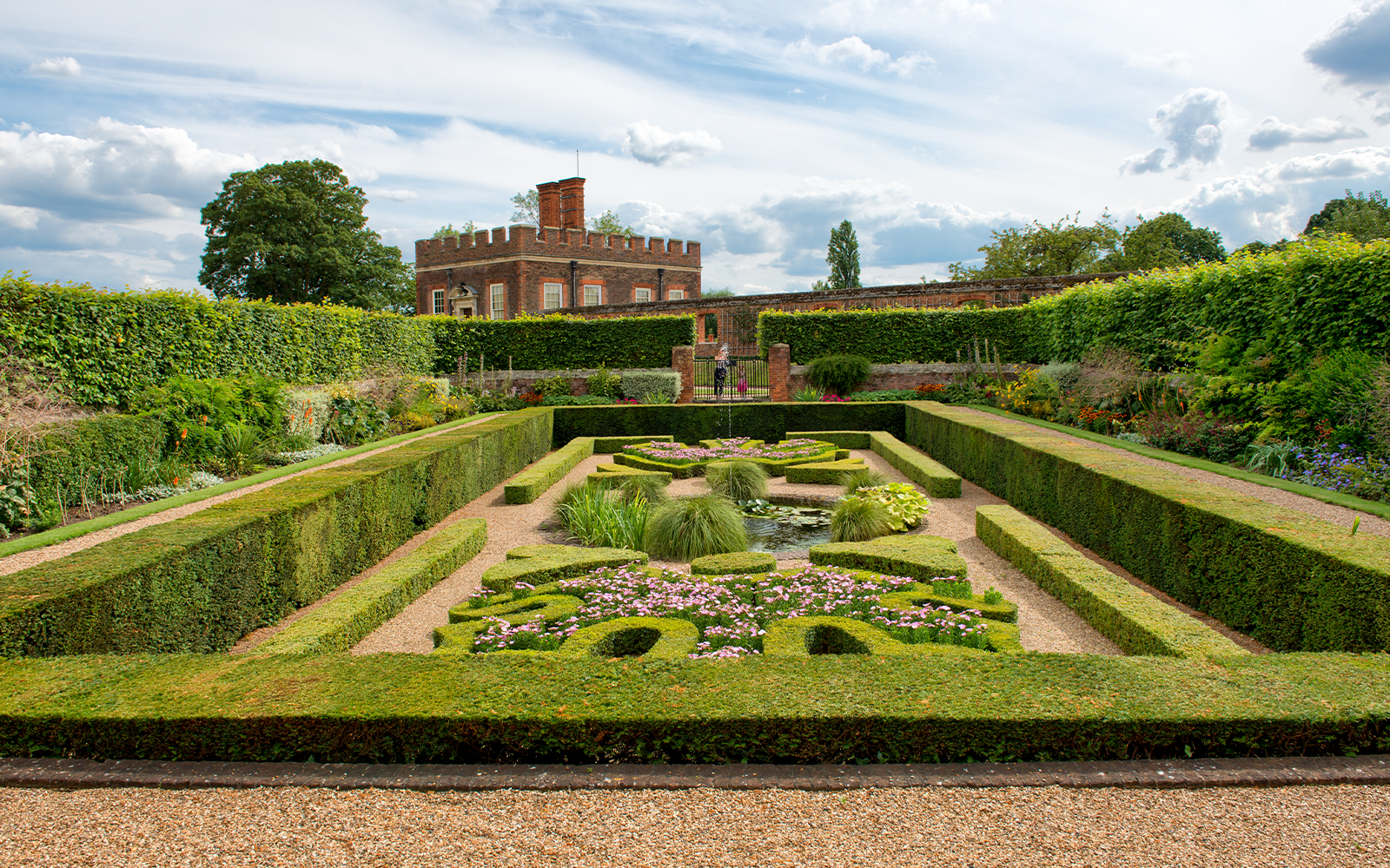 Visitors in Pond Gardens at Hampton Court Palace on a sunny day.
