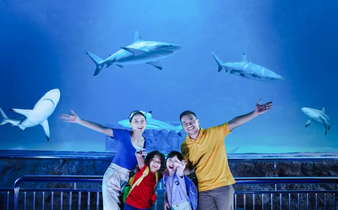 Family posing in front of shark tank at Sea World Ancol.