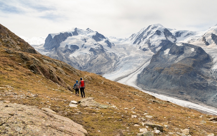 Visitors hiking towards Gornergrat viewing platform with snowy mountains in the background.