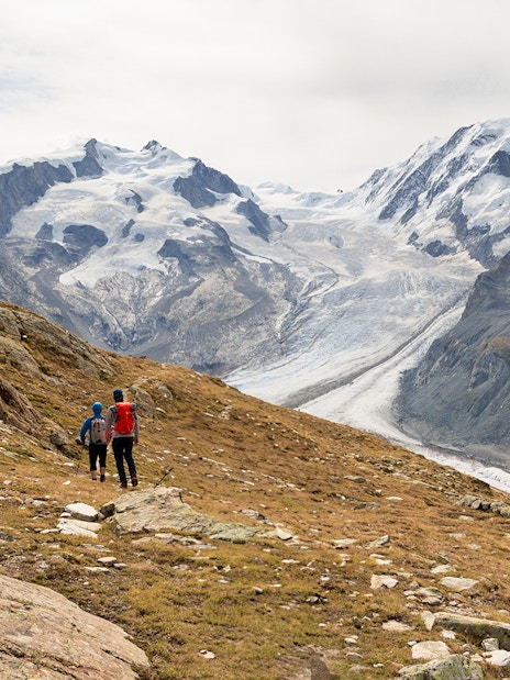 Visitors hiking towards Gornergrat viewing platform with snowy mountains in the background.