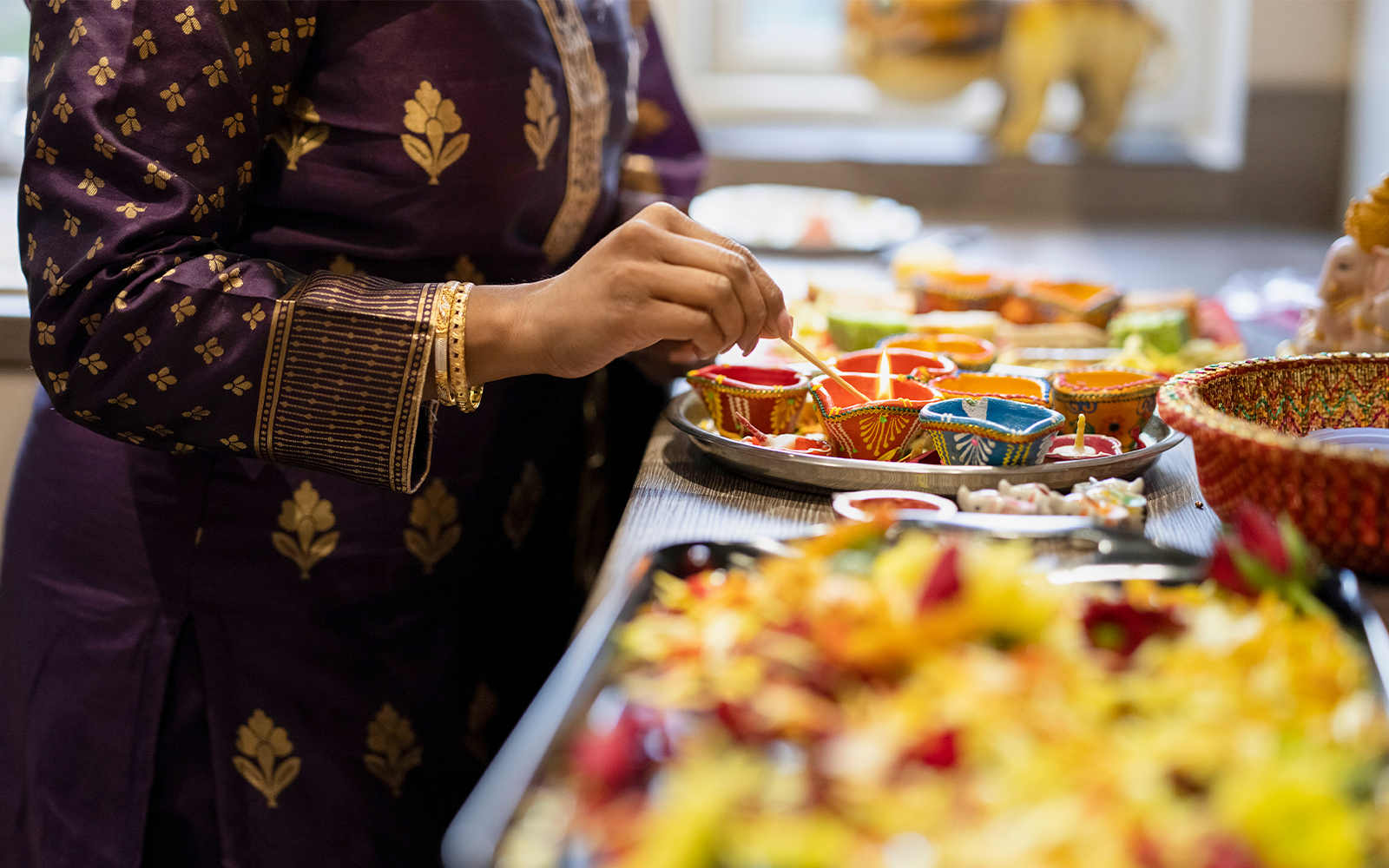 Woman preparing sweet snacks and diyas for Diwali celebration