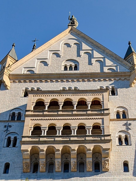 Neuschwanstein Castle facade close-up showing detailed stonework and arched windows.