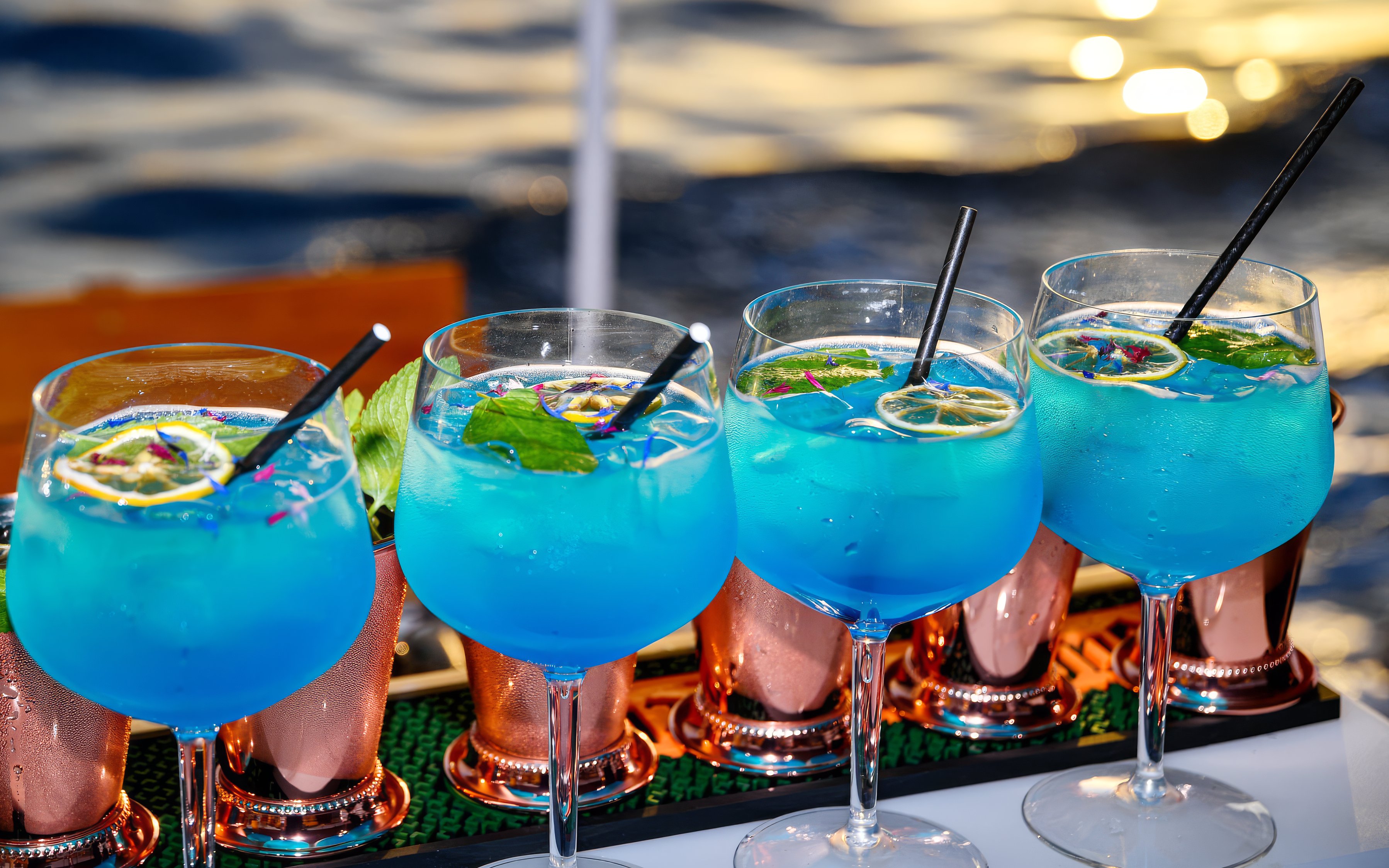 Blue cocktails with lime and mint served on a boat with ocean view.