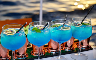 Blue cocktails with lime and mint served on a boat with ocean view.