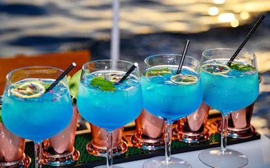 Blue cocktails with lime and mint served on a boat with ocean view.