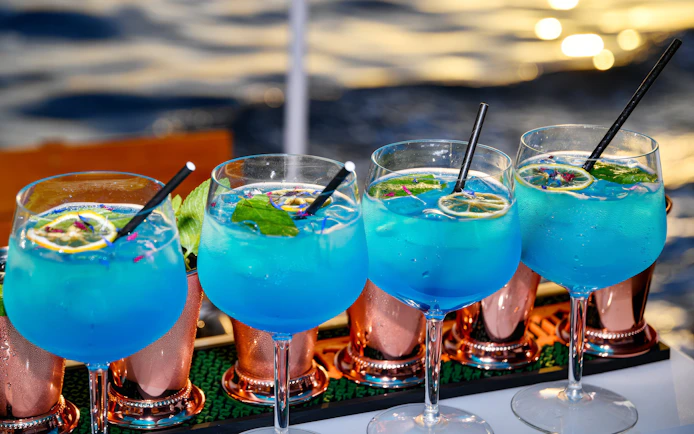 Blue cocktails with lime and mint served on a boat with ocean view.