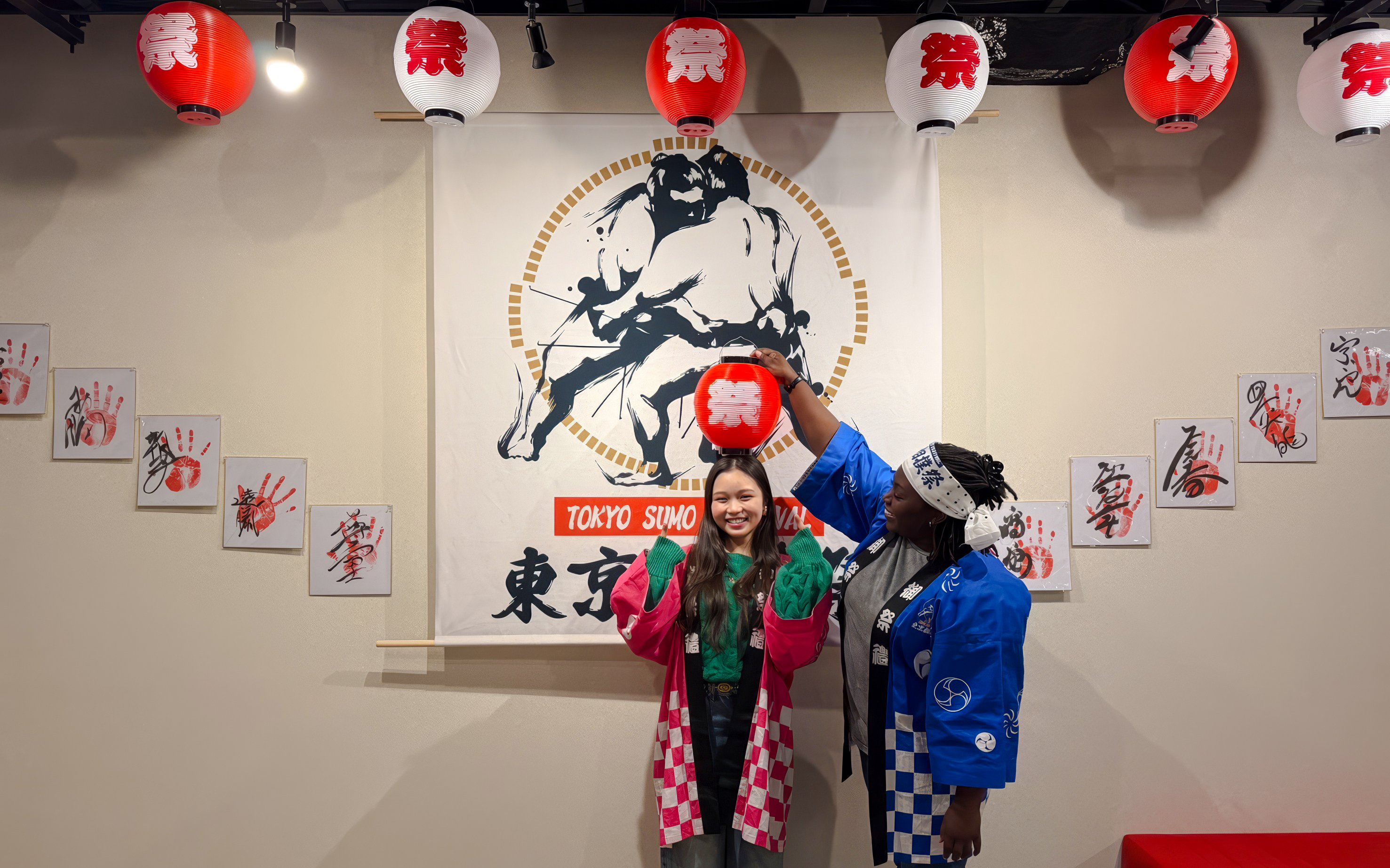 Visitors in traditional attire at Tokyo Sumo Festival in Ginza, posing with lanterns and sumo art.