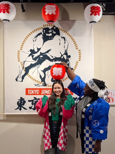 Visitors in traditional attire at Tokyo Sumo Festival in Ginza, posing with lanterns and sumo art.