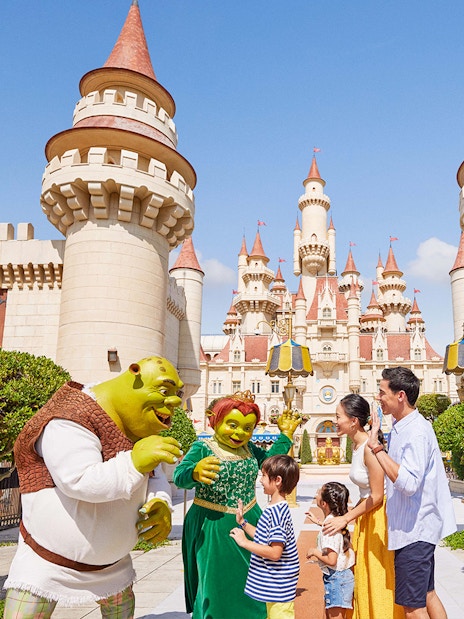 Family meeting Shrek characters at Universal Studios Singapore castle entrance.