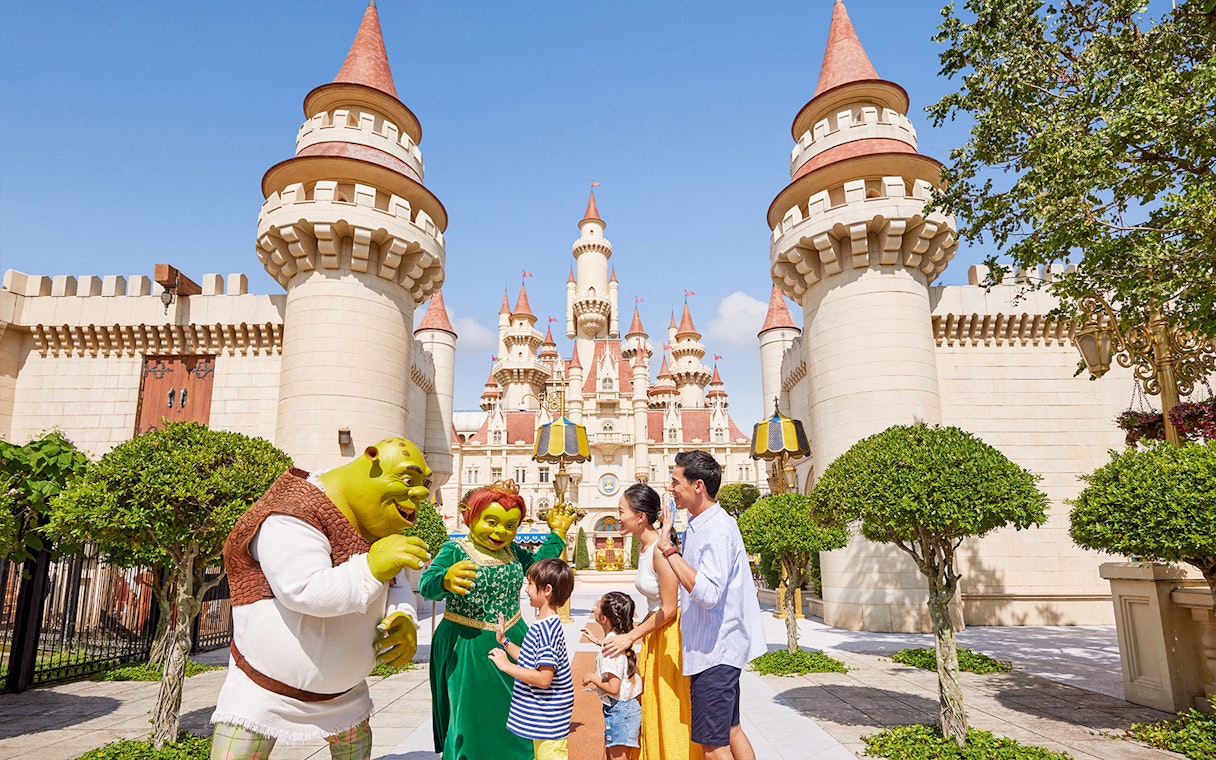 Family meeting Shrek characters at Universal Studios Singapore castle entrance.