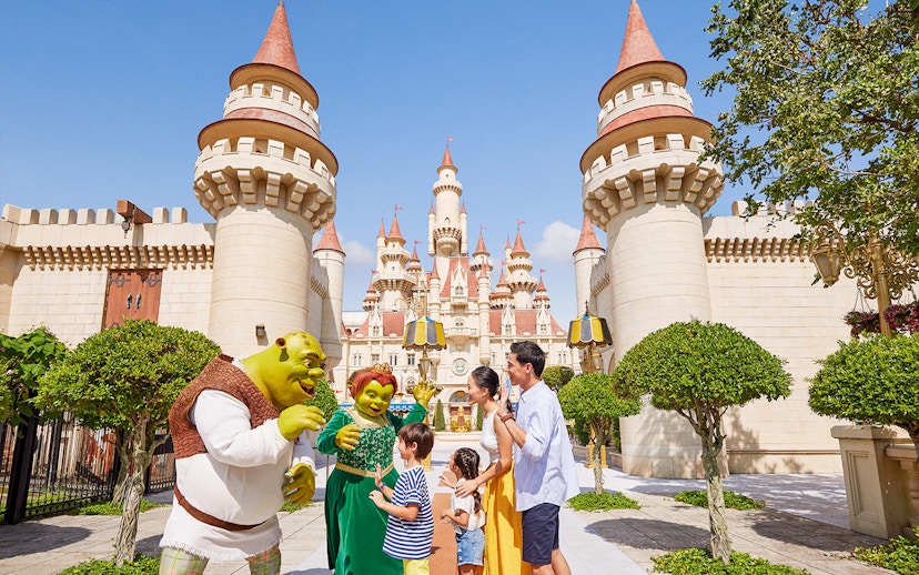 Family meeting Shrek characters at Universal Studios Singapore castle entrance.