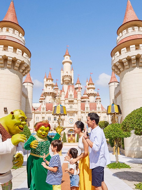 Family meeting Shrek characters at Universal Studios Singapore castle entrance.