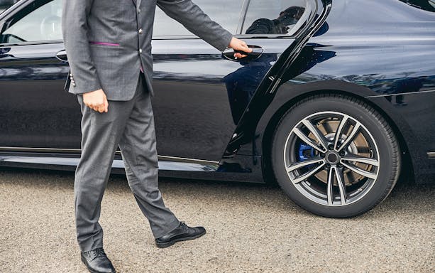 Chauffeur opening car door for Dubai & Abu Dhabi shuttle service.