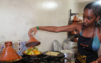 Traditional Moroccan tagine cooking class in Agadir, featuring a woman preparing vegetables.
