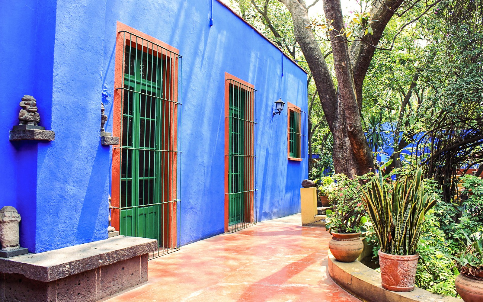 Frida Kahlo Museum exterior with vibrant blue walls and lush garden in Coyoacán, Mexico City.