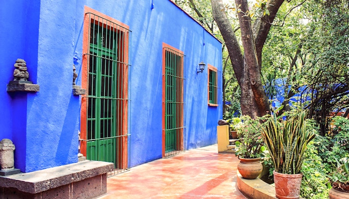 Frida Kahlo Museum exterior with vibrant blue walls and lush garden in Coyoacán, Mexico City.