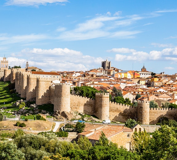 Ancient city walls surrounding Ávila, Spain, with historic buildings in the background.