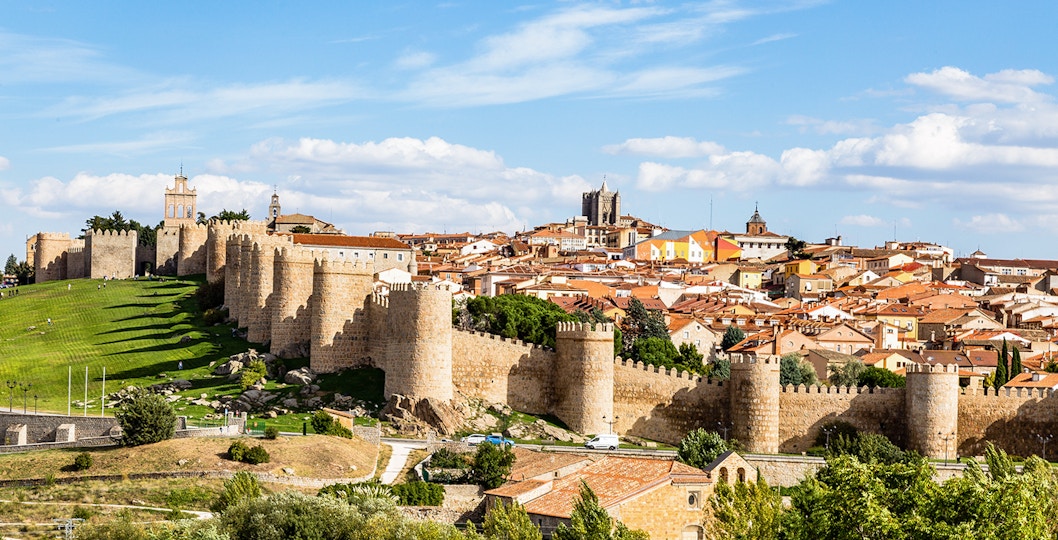Avila cityscape with medieval walls and cathedral, viewed from a distance.
