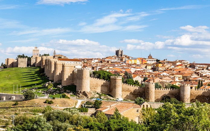 Avila cityscape with medieval walls and towers under a blue sky.