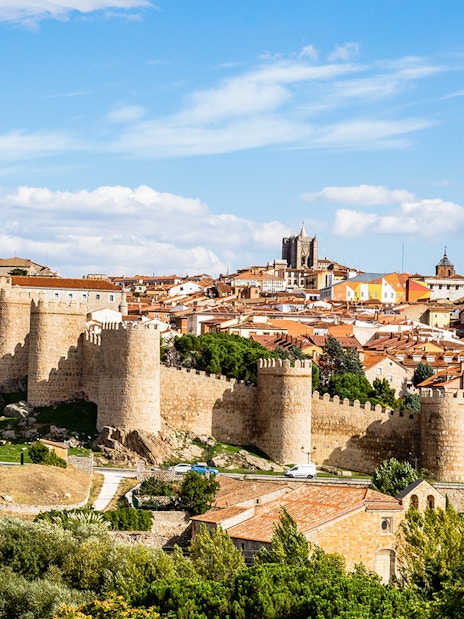 Avila cityscape with medieval walls and towers under a blue sky.