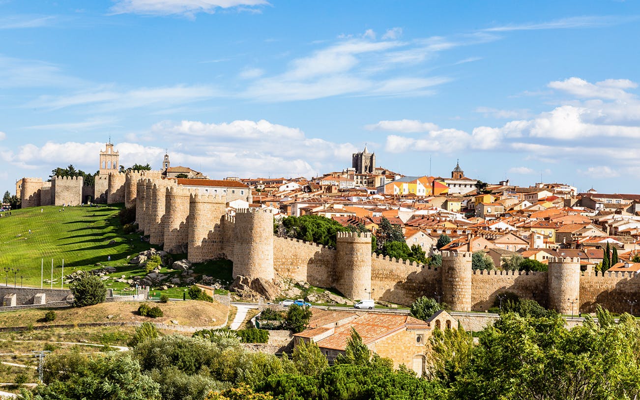 Avila cityscape with medieval walls and towers under a blue sky.