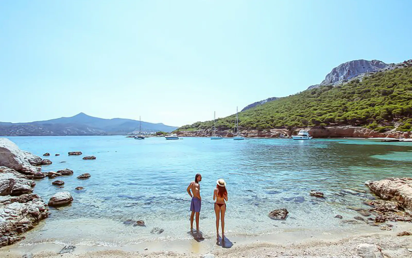 Guests enjoying the view on a beach during Athens Day Cruise with boats in the background.