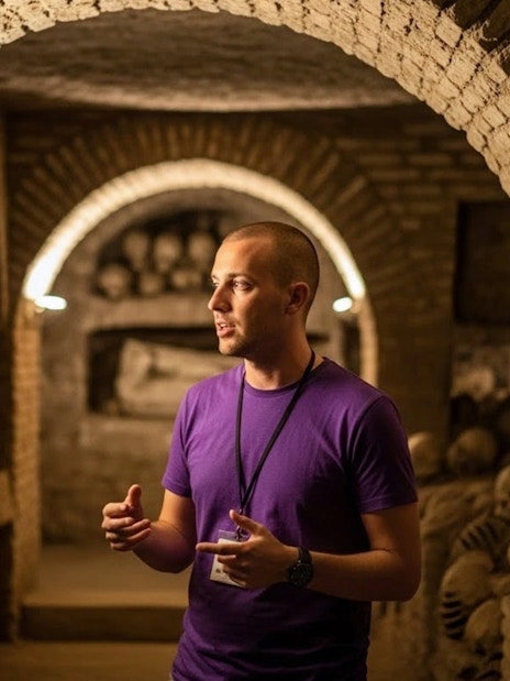 Guide explaining Roman catacombs with skulls and arches in the background.