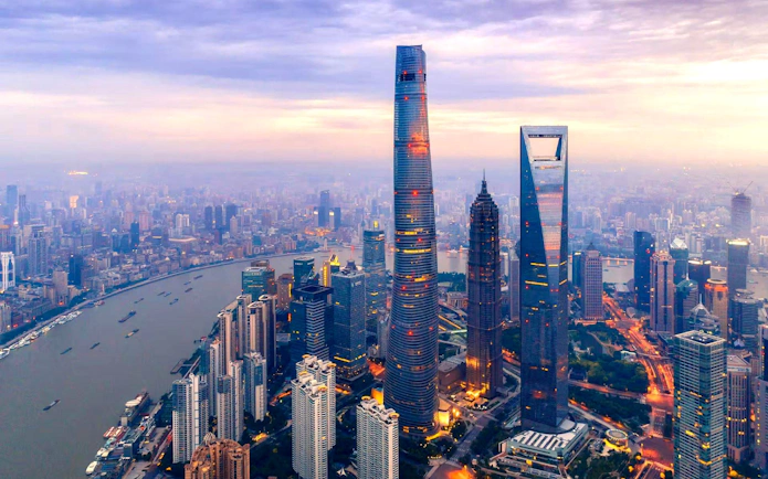 Shanghai skyline featuring the Shanghai Tower and Huangpu River at sunset.