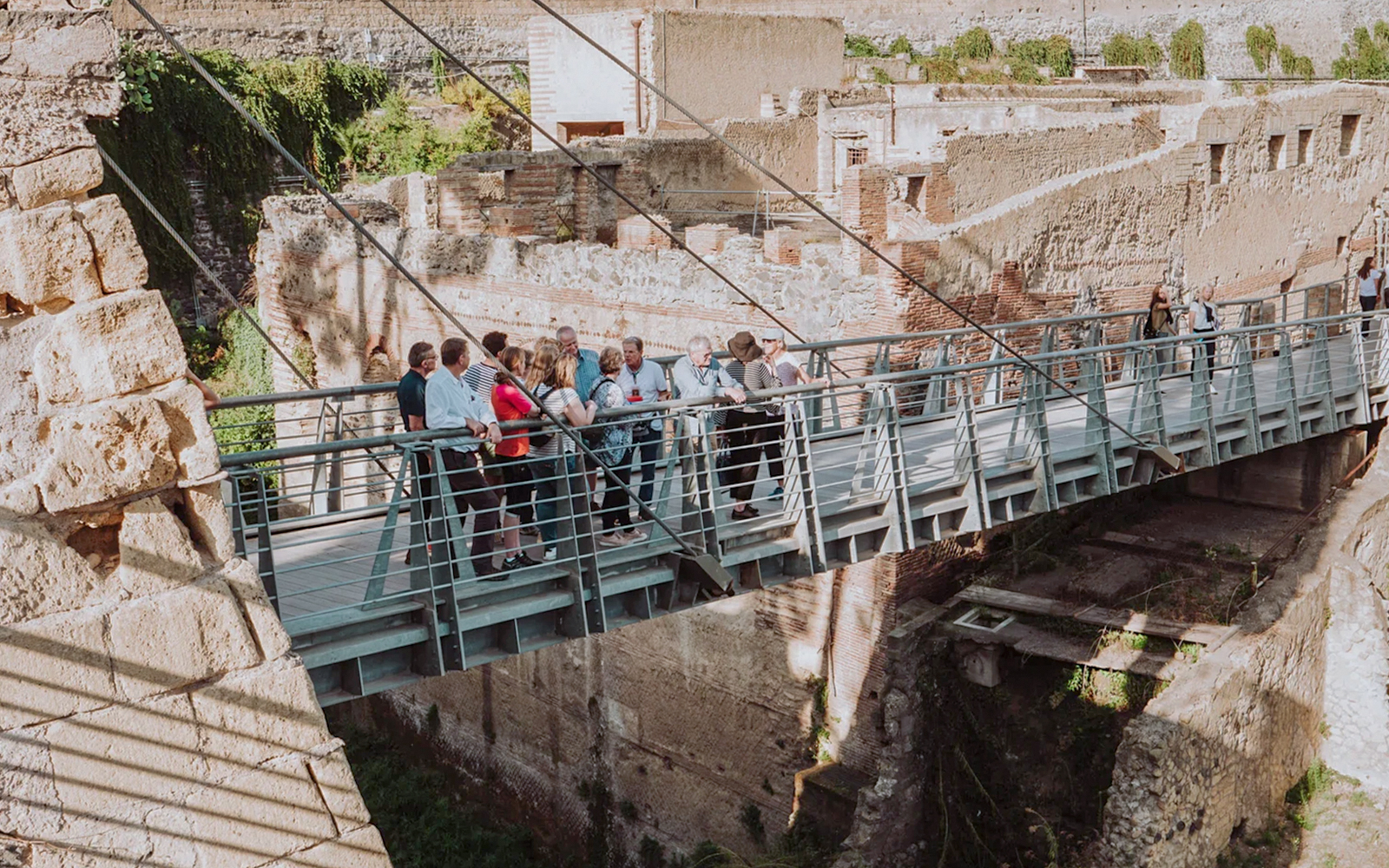 Group of tourists on a bridge at Herculaneum ruins during a guided tour from Naples.