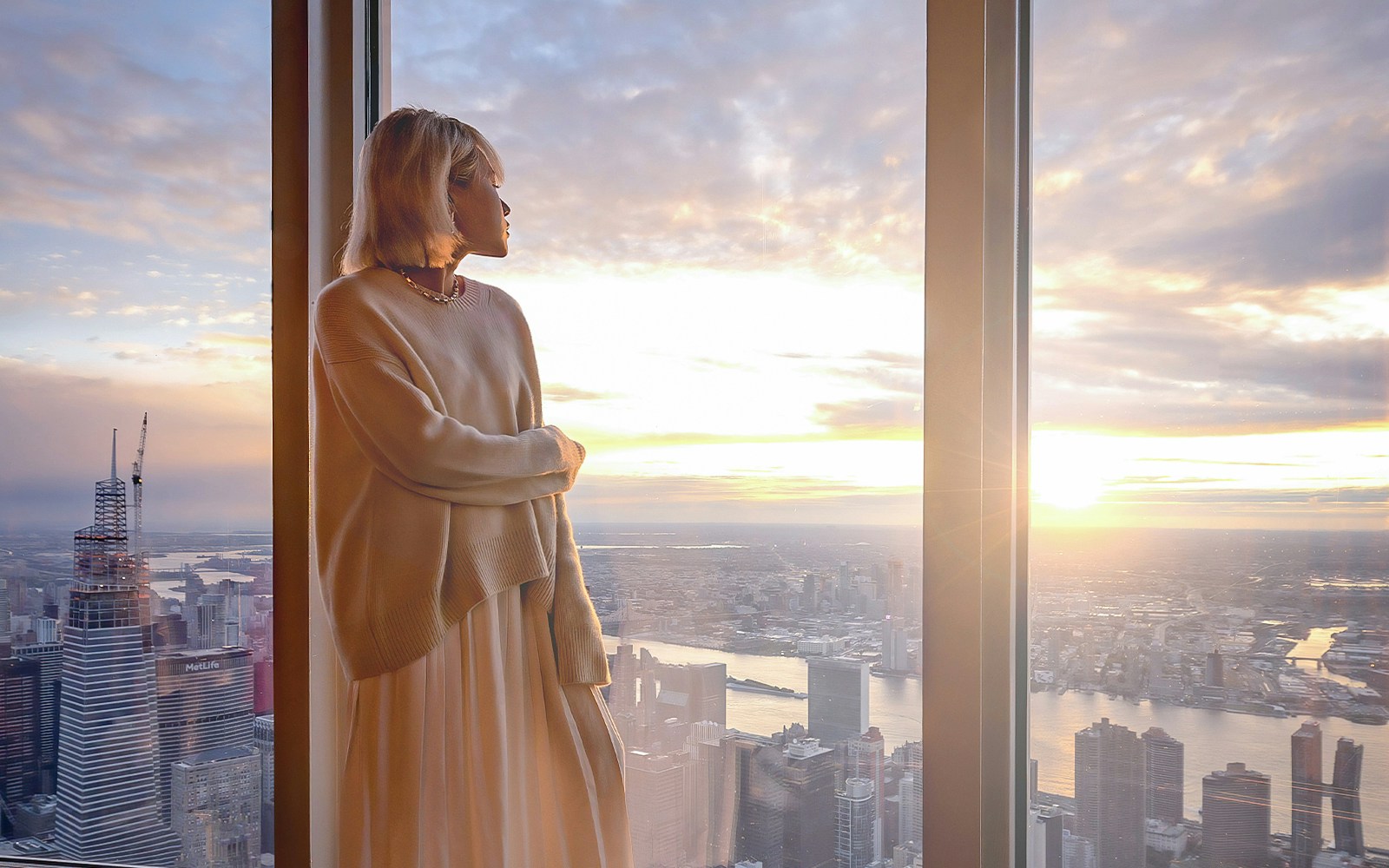 tourist enjoying views of new york skyline from Glass-enclosed observation deck on 102nd floor of empire state building