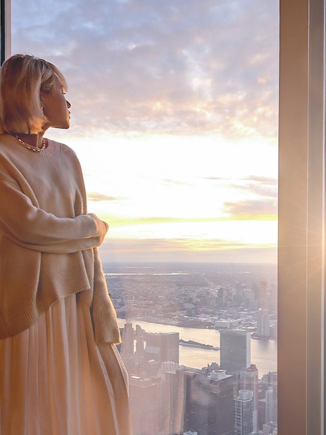 Person enjoying sunset view from a high-rise in New York City.