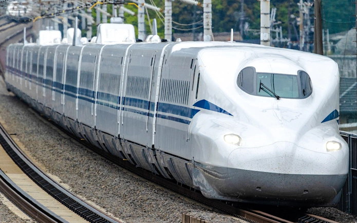 Shinkansen bullet train traveling on tracks in Japan.