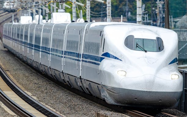 Shinkansen bullet train traveling on tracks in Japan.