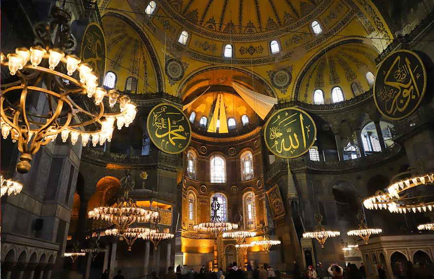 Hagia Sophia interior with chandeliers and Arabic calligraphy during guided tour.